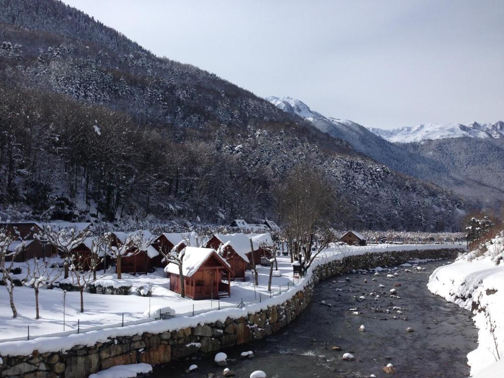 cabañas nevadas en camping junto al rio en pirineos