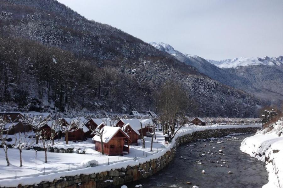 cabañas nevadas en camping junto al rio en pirineos